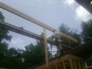 Carpenter setting a ridge beam over a new addition frame — Ice Dam Removal by Roofing Brothers in Oyster Bay