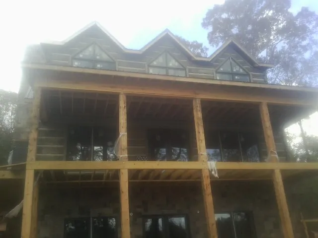 Dormers and porch framing on a large log home under construction — Roof Coating work by our crew in Oyster Bay