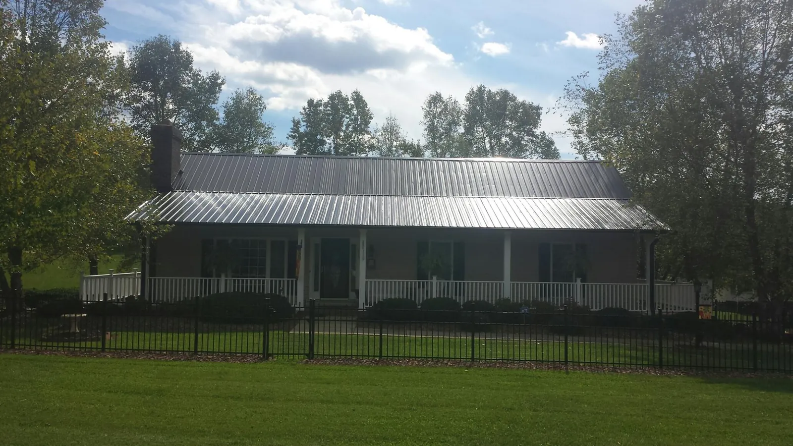 Gray metal roof on a brick ranch with a full width front porch — Gutter Guard Installation work by our crew in Oyster Bay