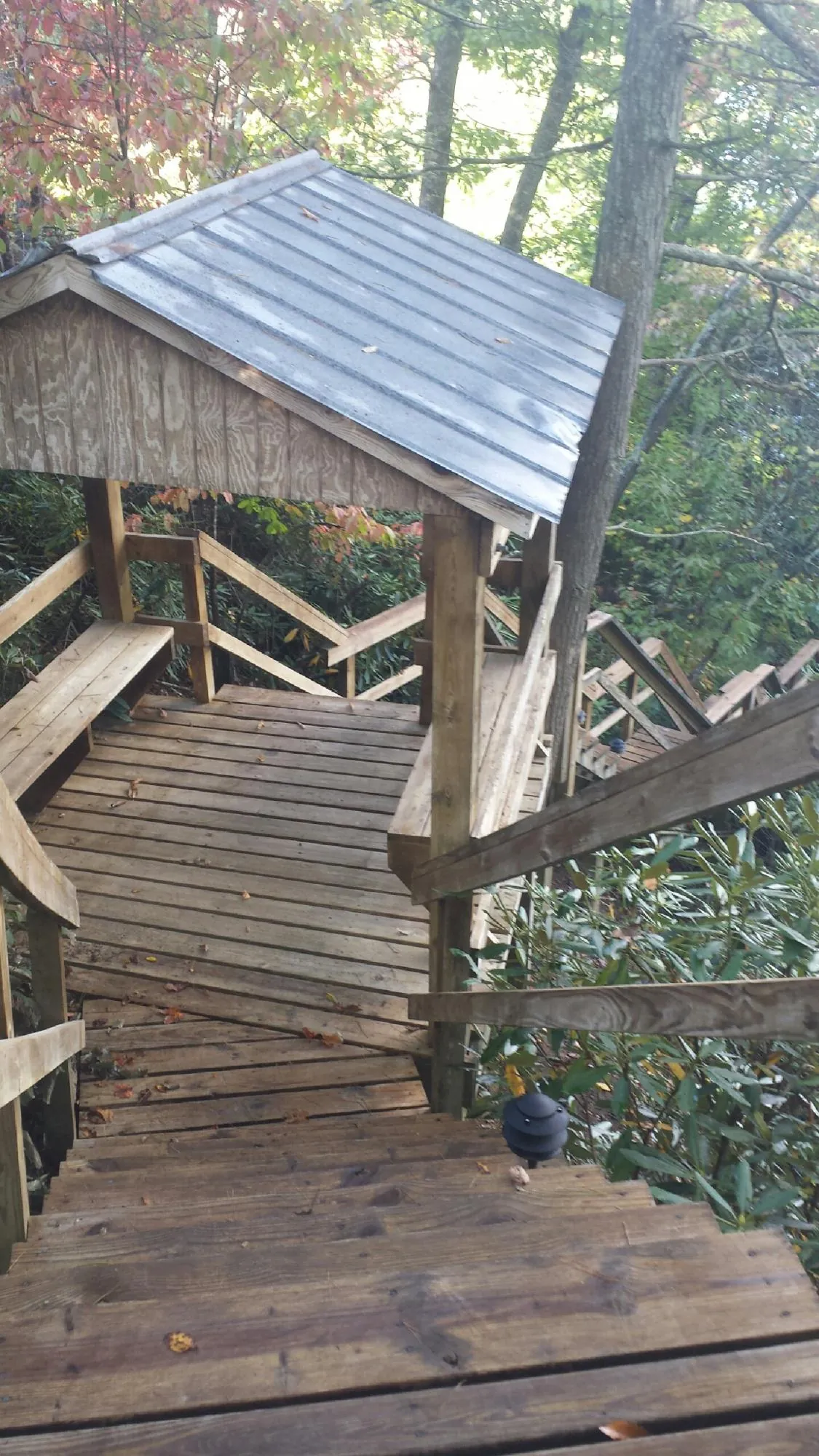 Metal roofed shelter over wooden steps on a wooded walkway — Skylight Repair & Installation work by our crew in Oyster Bay