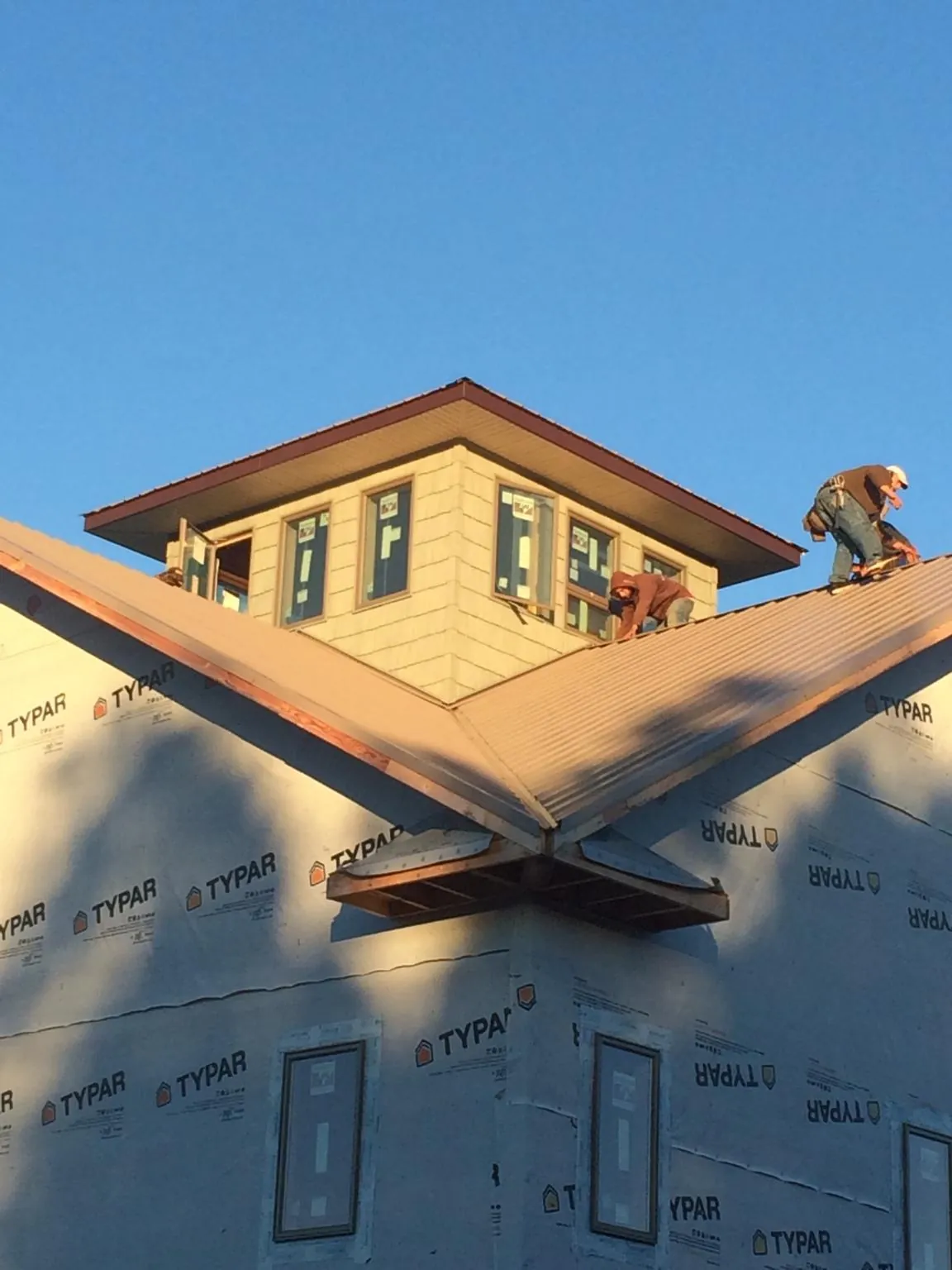 Roofers working around a rooftop cupola on a new metal roof at sunset — Roof Waterproofing in Oyster Bay by Roofing Brothers